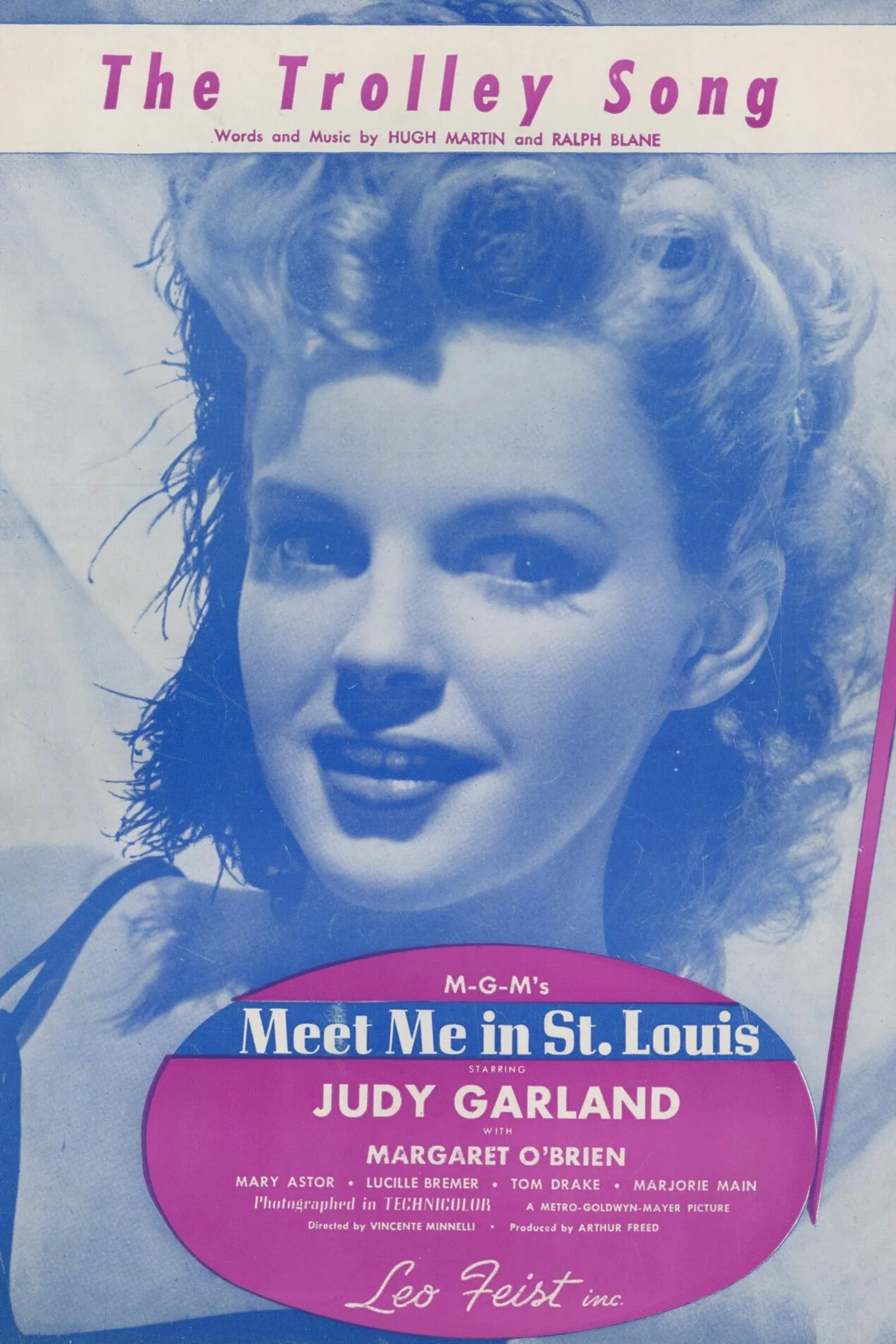 A sheet music cover for "The Trolley Song" with a blue-toned photograph of Judy Garland. At the bottom, it says in white text within a pink oval, "M-G-M's Meet Me in St. Louis starring Judy Garland with Margaret O'Brien, Mary Astor, Lucille Bremer, Tom Drake, Marjorie Main. Photographed in technicolor. A Metro-Goldwyn-Mayer picture. Directed by Vincete Minelli. Produced by Arthur Freed. Leo Feist inc."