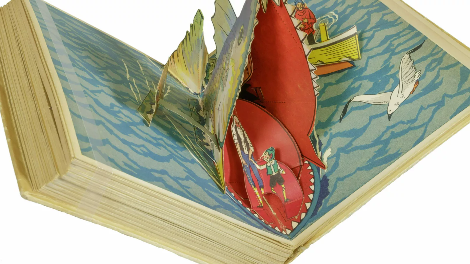 A whale's mouth opens in a pop-up book. Inside the whale's mouth are Pinocchio and Geppettoo
