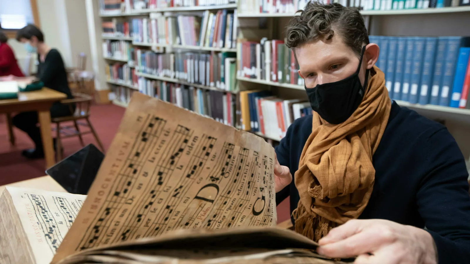 A researcher turns the pages of a book of music