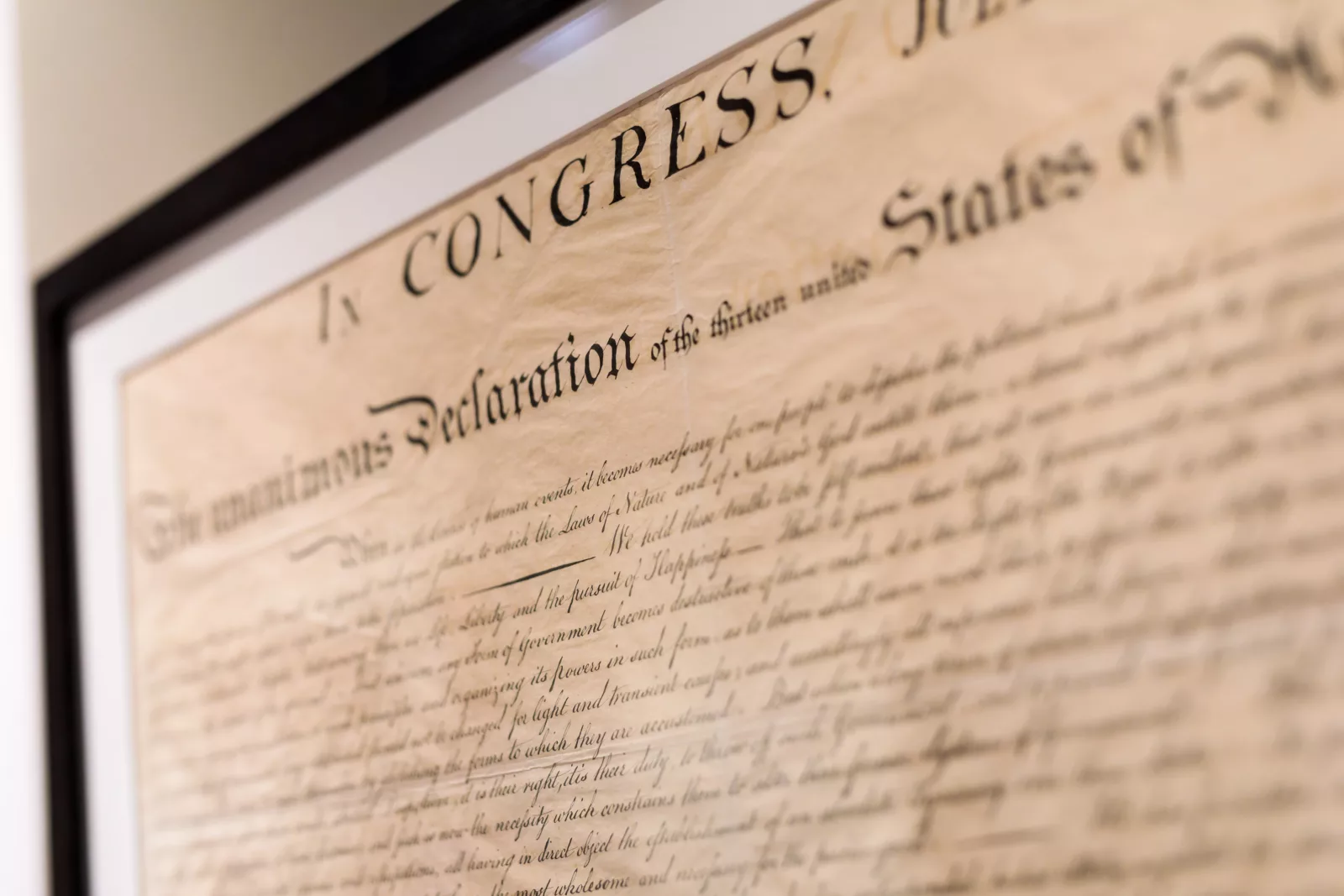 The text of the Declaration of Independence appears on display under glass. Though the text appears to be handwritten, it was actually engraved.
