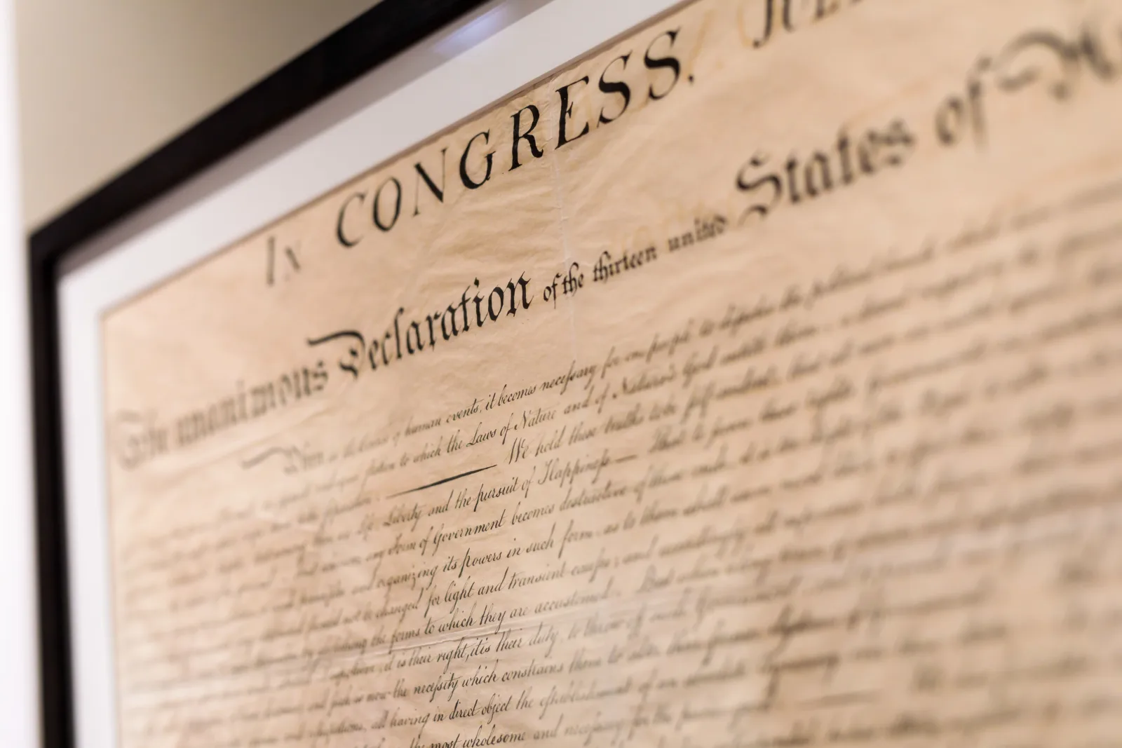 The text of the Declaration of Independence appears on display under glass. Though the text appears to be handwritten, it was actually engraved.