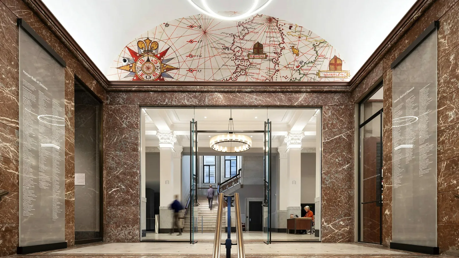 Image of the interior Front Entrance Hall to the Newberry Building, a red granite walled stairway leading up to a glass doorway. The ceiling is barrel vaulted in the front hall; in the arch above the doorway is the representation a map and its compass rose.