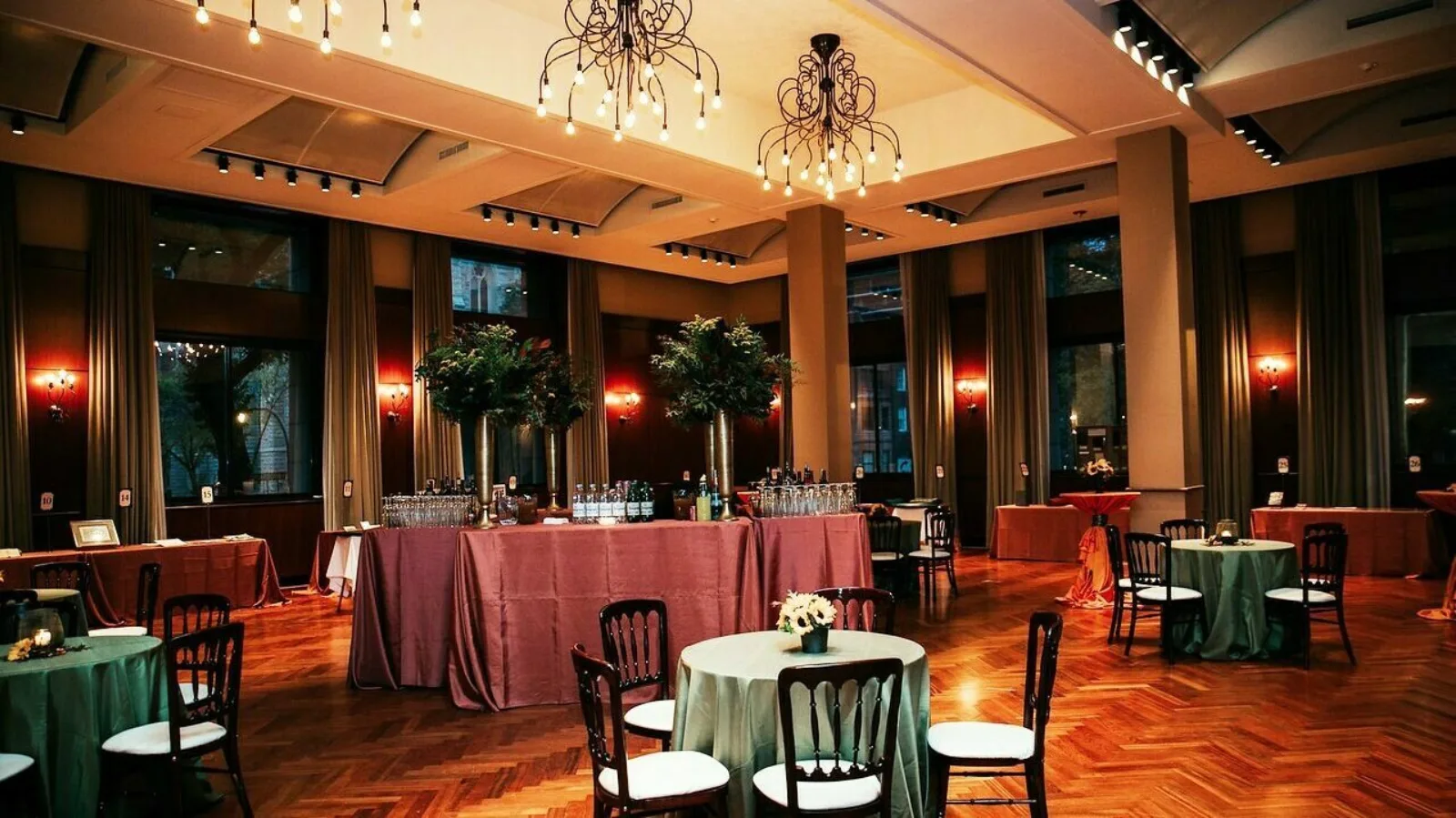 A bar is stationed in the center of a banquet room with tables set up around it.