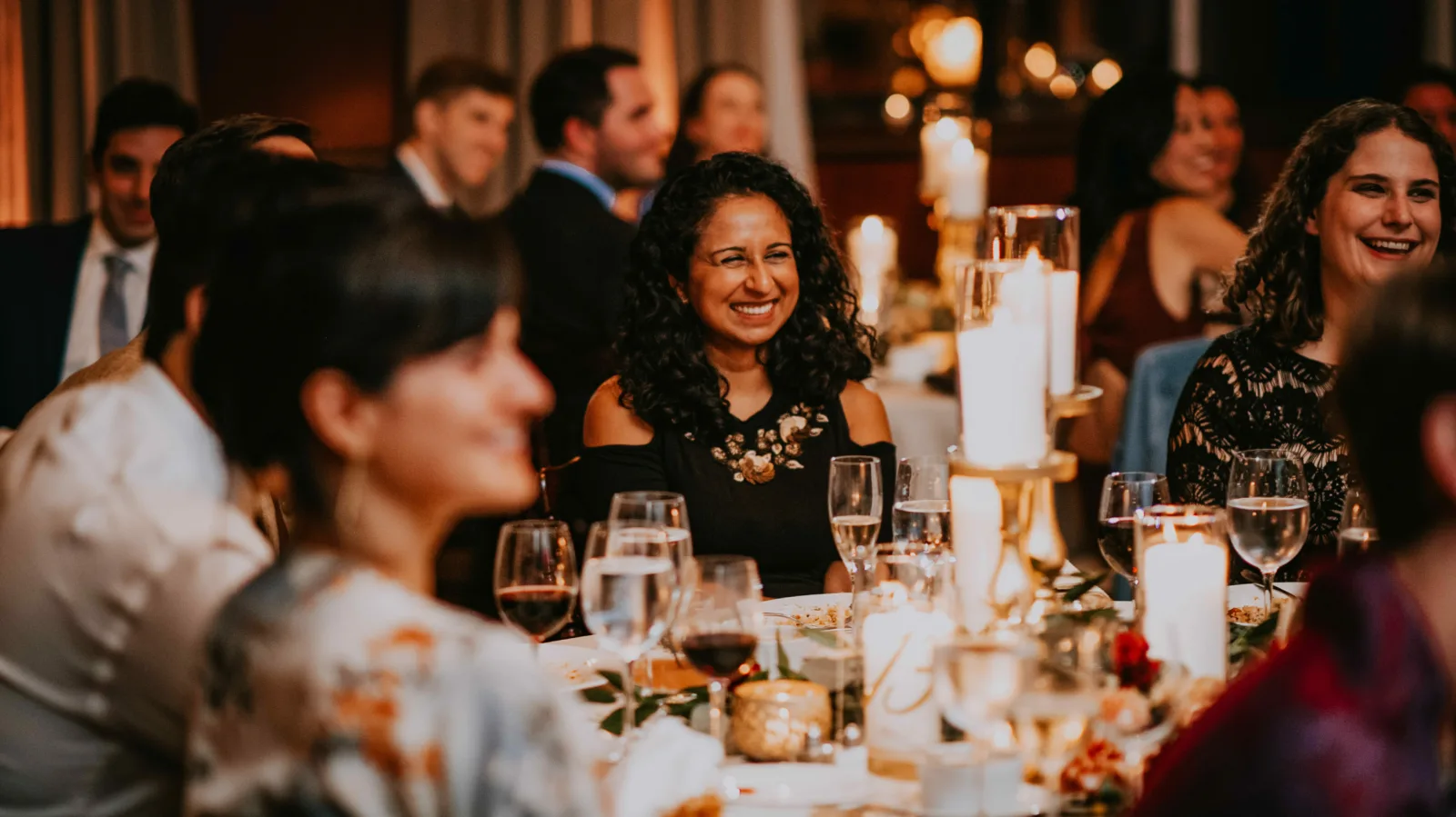 Guests seated in Ruggles Hall People sit at tables in a banquet room. They are smiling and laughing.