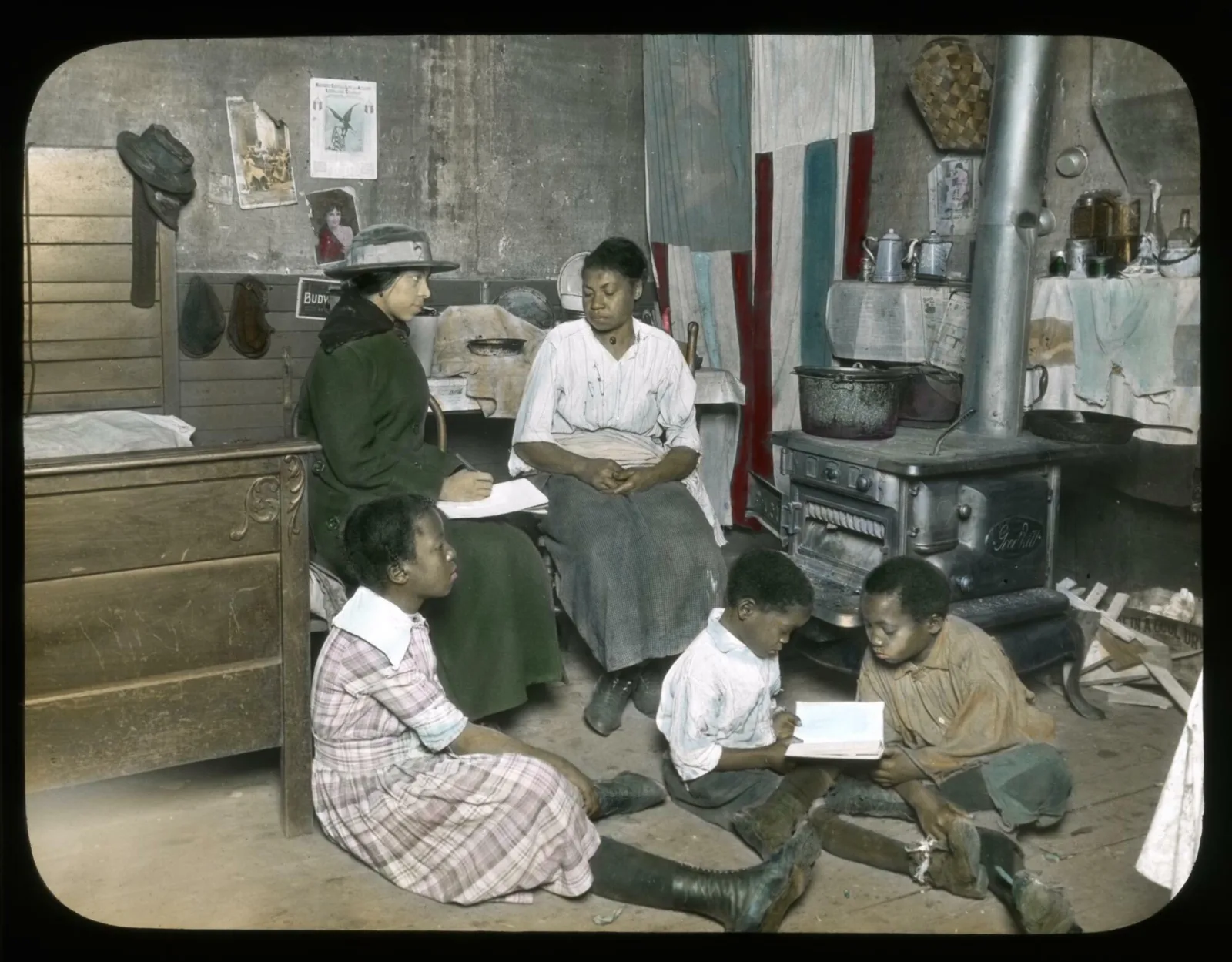 Social service worker meets with a mother and her family A social service worker sits on a chair next to a woman. Three children sit on the floor and look at a book together.