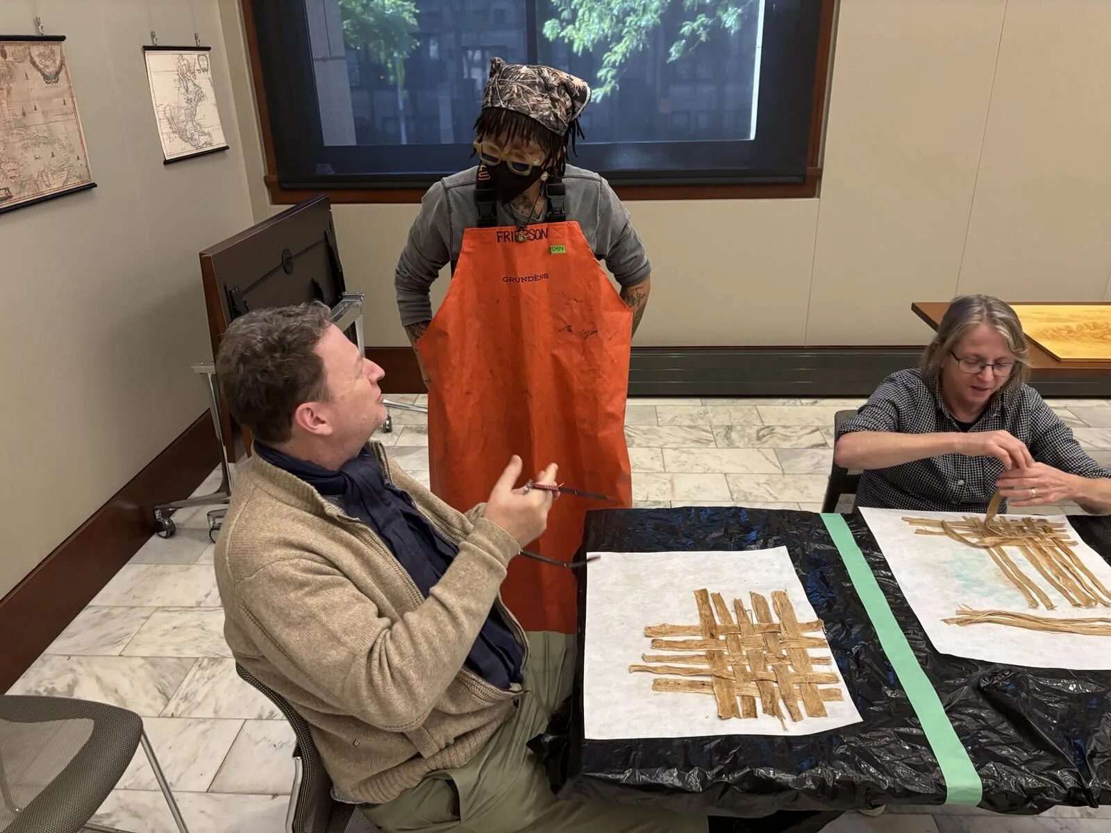 A Patron Assembles Fiber Weave Instructor discusses paper making with particpant. Participant arranges fibers.