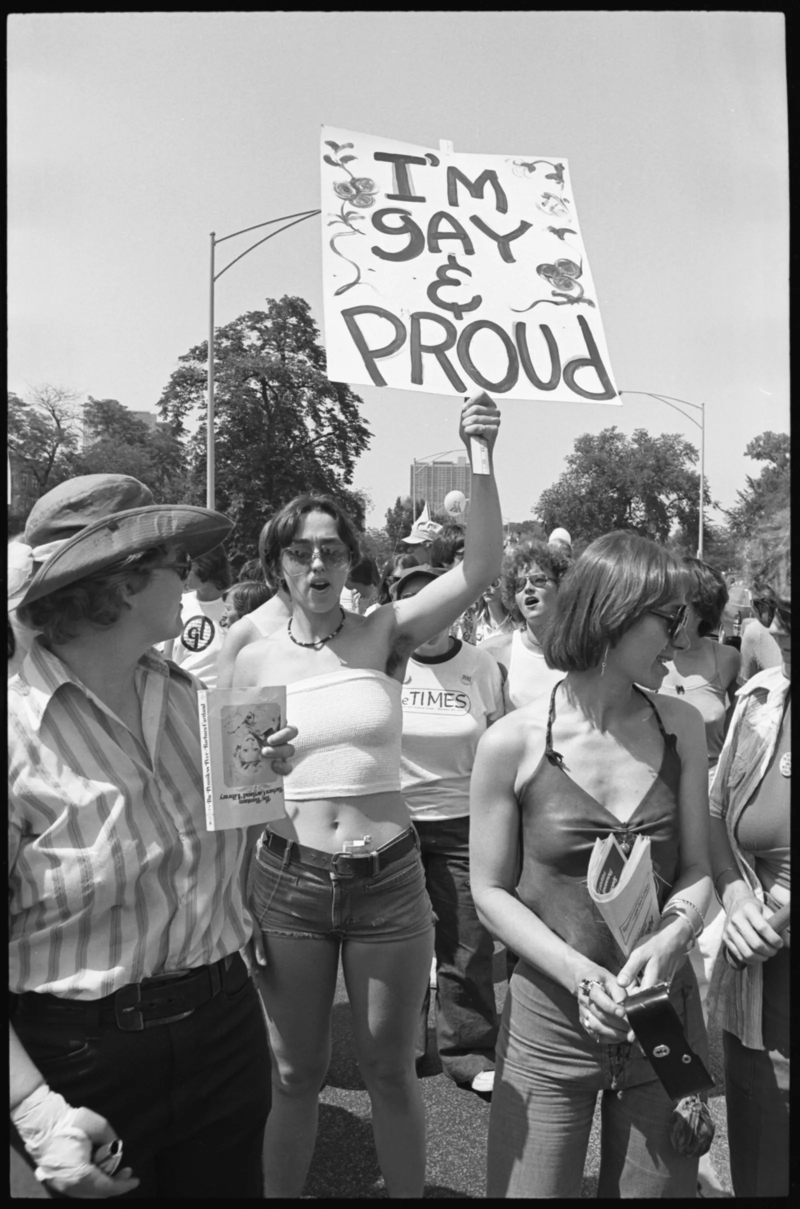 A woman holds a sign that reads "I'm Gay and I'm Proud"