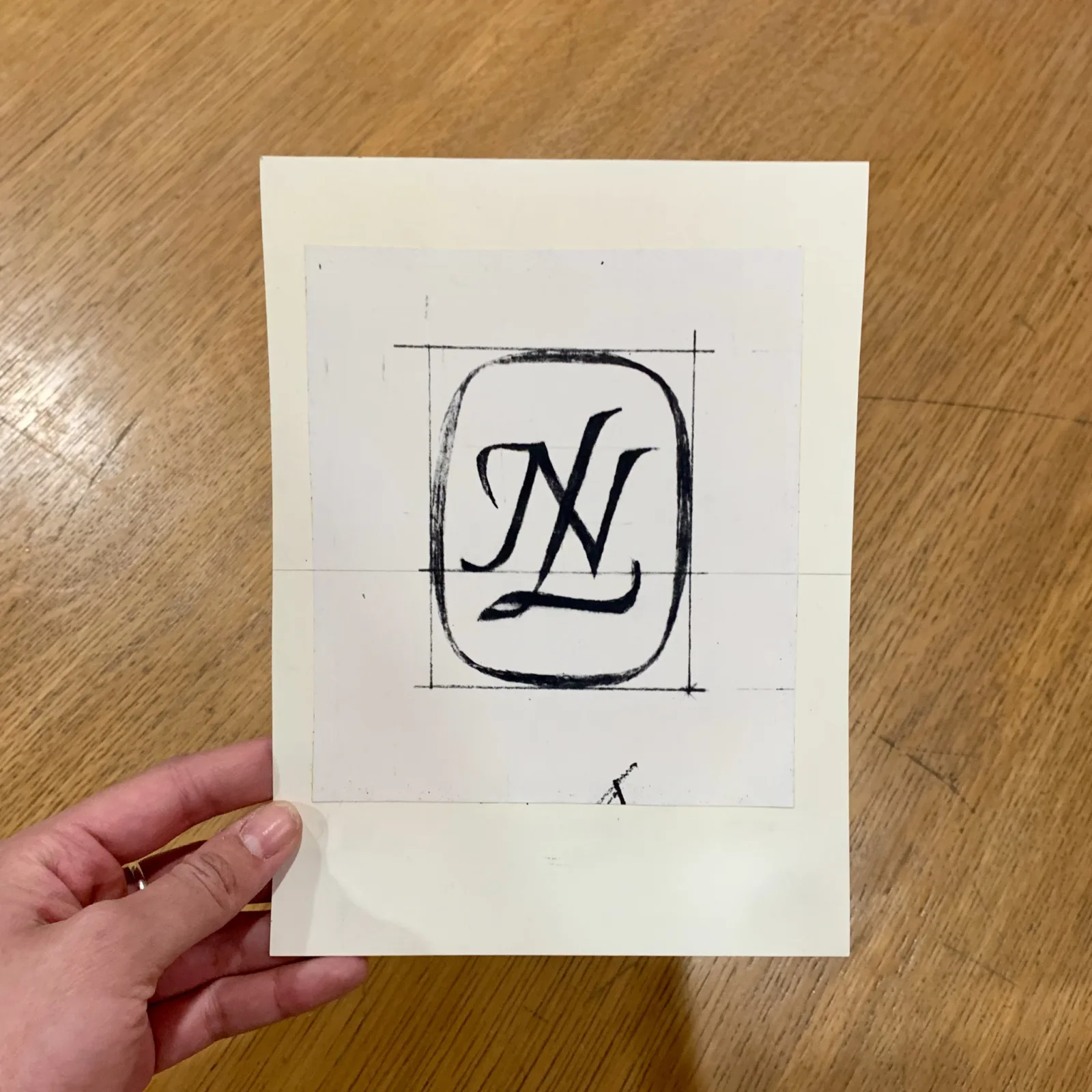 NL written in script with an oval surrounding it.