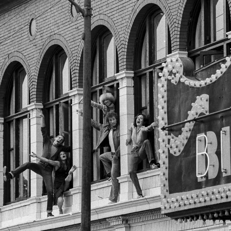 Five dancers from the Chicago Moving Company pose out of a window on the outside of the Biograph Theater.